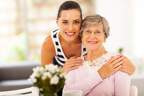 Daughter smiling leaned down embracing smiling mother's shoulders